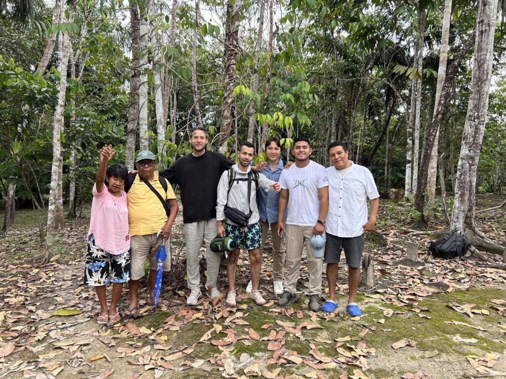 Group photo in the Peruvian Amazon featuring participants and facilitators of the Ayahuasca retreat, including local shamans and travelers, standing together in the rainforest after a powerful shared healing experience.