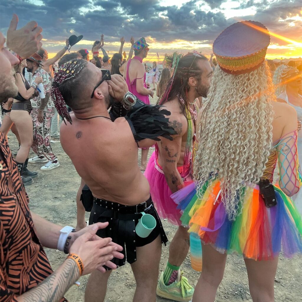 Colorfully dressed participants dance at sunset during AfrikaBurn, celebrating radical self-expression, joy, and community
