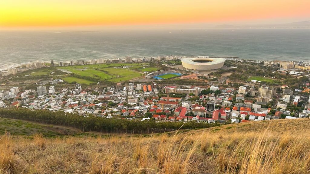 Aerial view of Cape Town Stadium and cityscape at sunset, highlighting the scenic beauty and lifestyle appeal of South Africa’s Mother City
