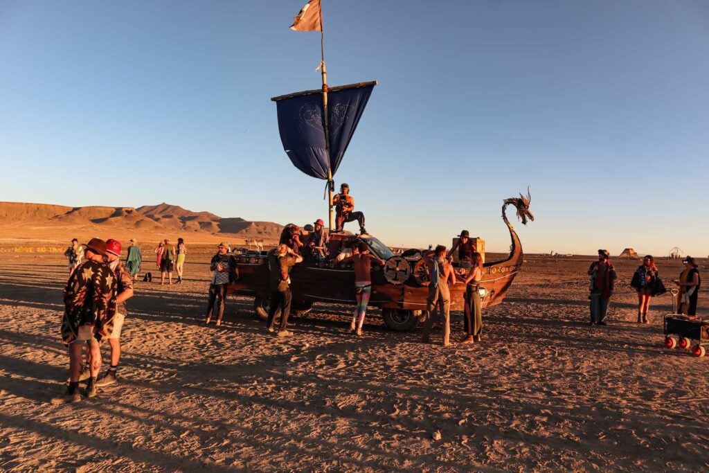 Participants gather around a Viking ship mutant vehicle at AfrikaBurn, showcasing creativity and desert art culture in South Africa