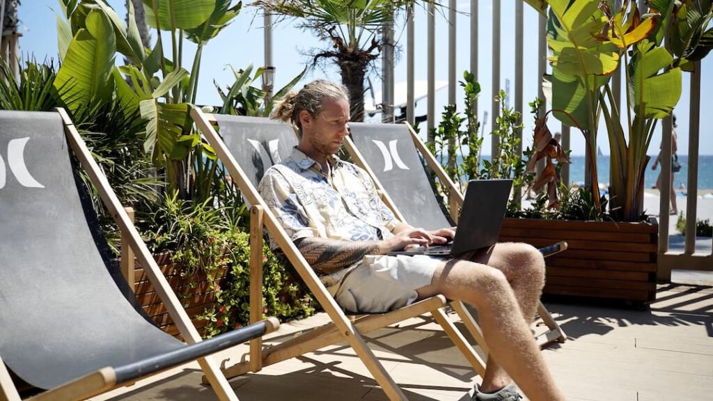 Remote performance marketer working from a beachside lounge chair, showing the freedom of the digital nomad lifestyle